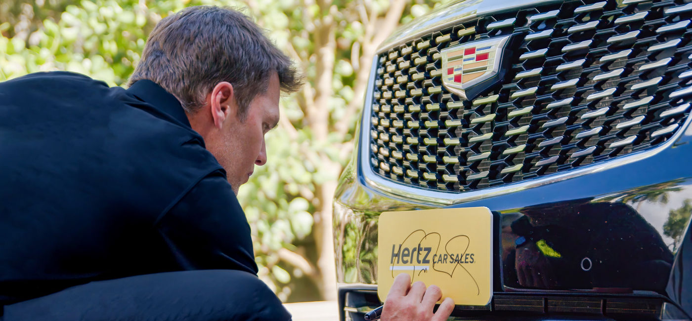 Image: Tom Brady signs Hertz car. (Photo Credit: Hertz Media)