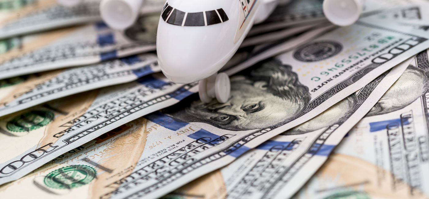 Image: Airplane on dollar bills. (Photo Credit: RomanR / Adobe Stock)