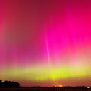 Rare pink and green Northern Lights illuminate the night sky.