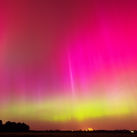 Rare pink and green Northern Lights illuminate the night sky.