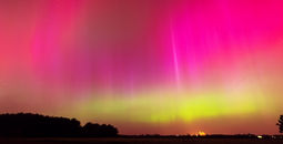 Rare pink and green Northern Lights illuminate the night sky.