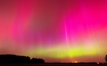 Rare pink and green Northern Lights illuminate the night sky.