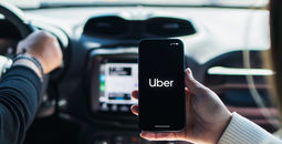 Car passenger using the Uber app on her mobile phone.