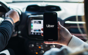 Car passenger using the Uber app on her mobile phone.