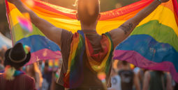 Person holding an LGBTQ+ Pride flag.