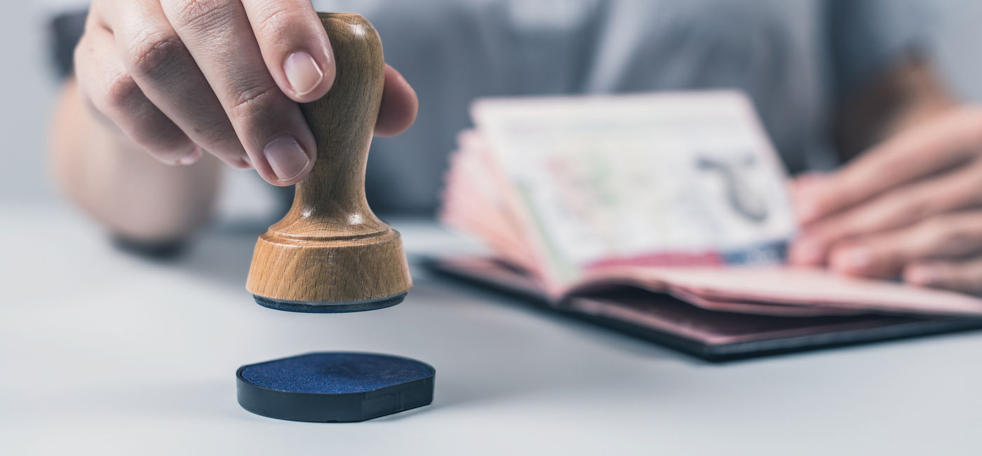 Image: PHOTO: Customs and Immigration Control officer stamping a passport. (Photo via iStock/Getty Images Plus/FTiare)