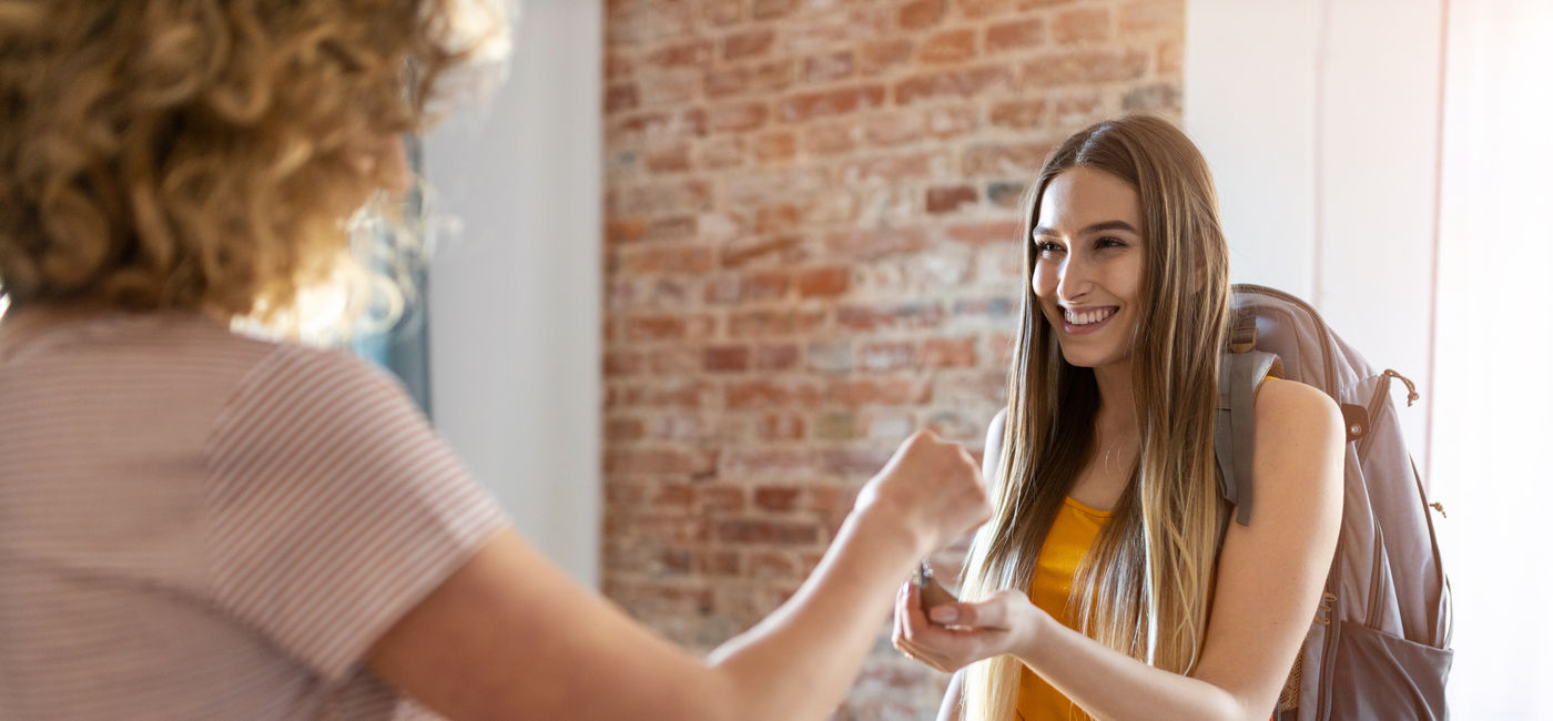 Image: Female traveler receiving the keys to a short-term rental property. (Photo Credit: Adobe/pikselstock)