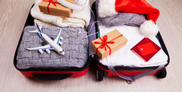 Suitcase with Christmas gifts and a Santa hat.