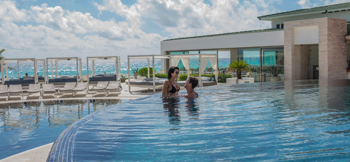 Image: Couple enjoying the pool at Sandos Cancun. (Photo Credit: Sandos Resorts)