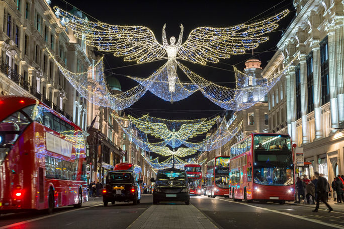 Double-decker buses pass beneath Christmas lights on Regent Street, London, U.K.