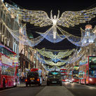 Double-decker buses pass beneath Christmas lights on Regent Street, London, U.K.