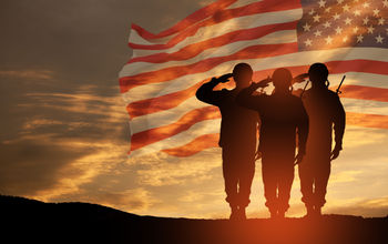 USA army soldiers saluting on a background of sunset or sunrise and USA flag.