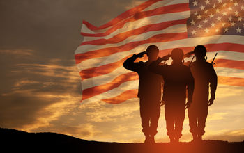 USA army soldiers saluting on a background of sunset or sunrise and USA flag.