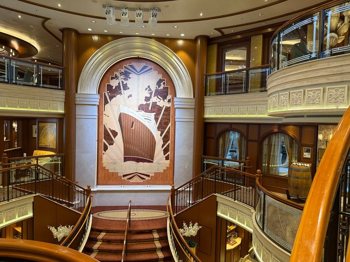The ship’s triple-height atrium features a stunning marquetry panel depicting the original RMS Queen Elizabeth.