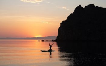 A paddleboarder rejoices in the beauty of the sunset in Loreto, Baja California.