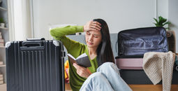 A traveler feeling stressed while packing for her trip.