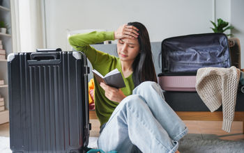 A traveler feeling stressed while packing for her trip.