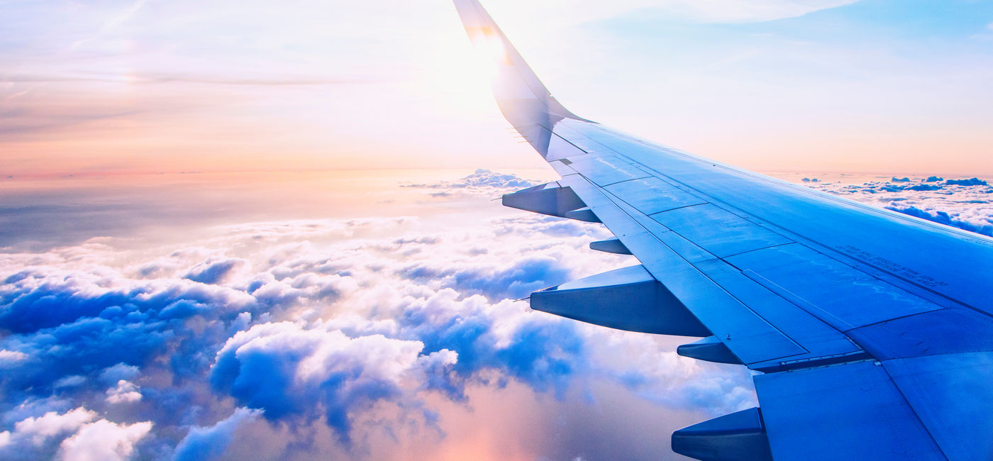 Image: View over the wing of an airplane in flight. (Photo Credit: babaroga / Adobe Stock)