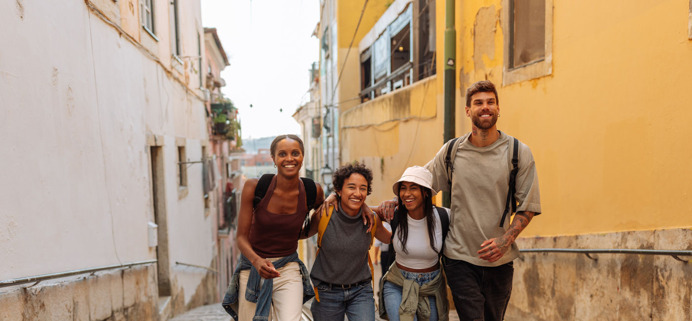 Image: Gen Z travelers walking down the street in Lisbon, Portugal. (Photo Credit: bernardbodo / Adobe Stock)