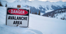 Avalanche danger area sign in a snowy mountain landscape.