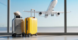 Luggage sitting at the airport with a plane taking off in the background.