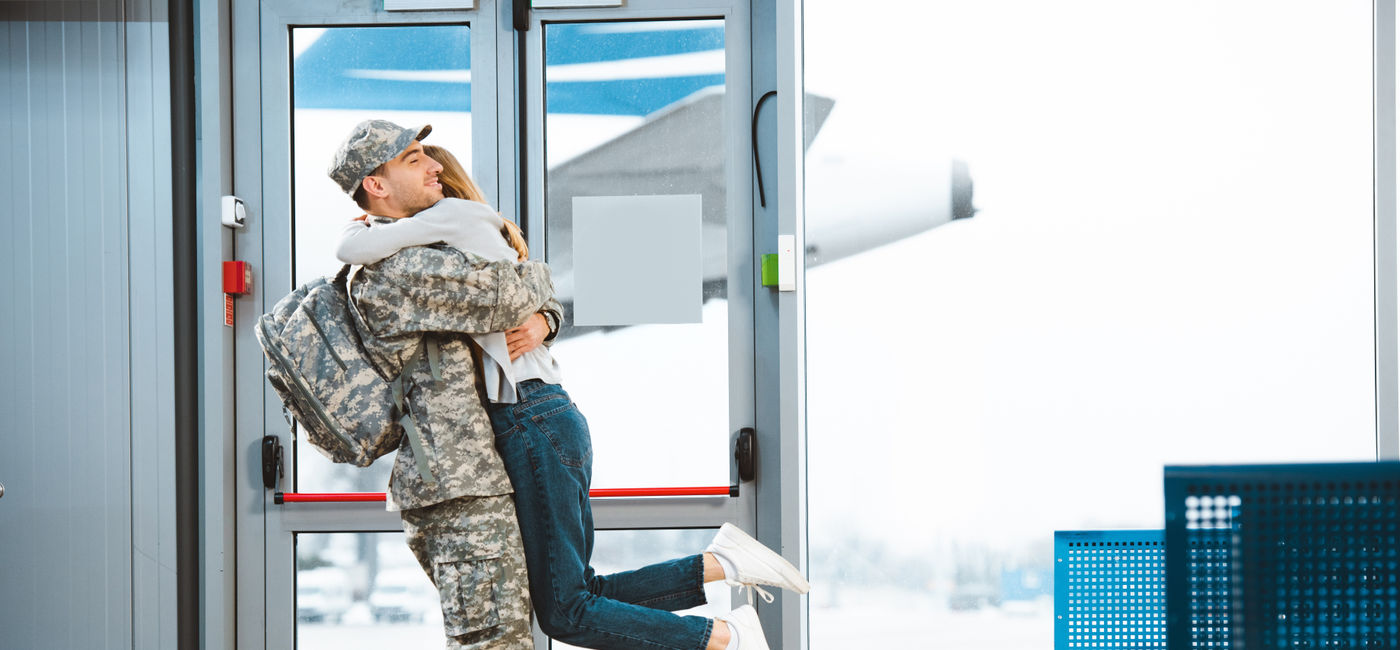 Image: Woman greets military spouse at airport.  (Photo Credit: LIGHTFIELD STUDIOS / Adobe Stock)