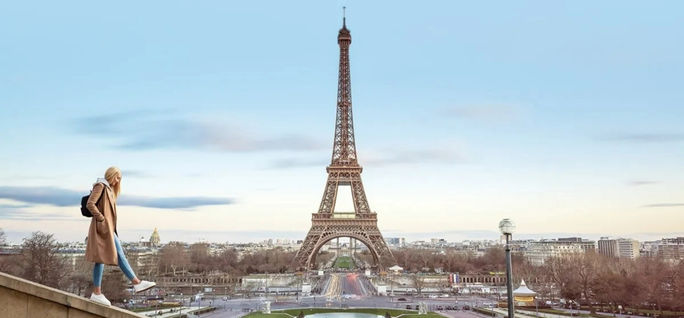 Eine junge Frau geht am Eiffelturm in Paris vorbei. Contiki, Paris, Millennial Travel, junge Frau, junge Reisende, Reisende