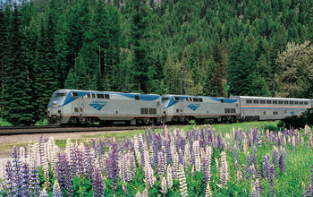 An Amtrak long-distance train travels through the lush forests and wildflower meadows of the Pacific Northwest.