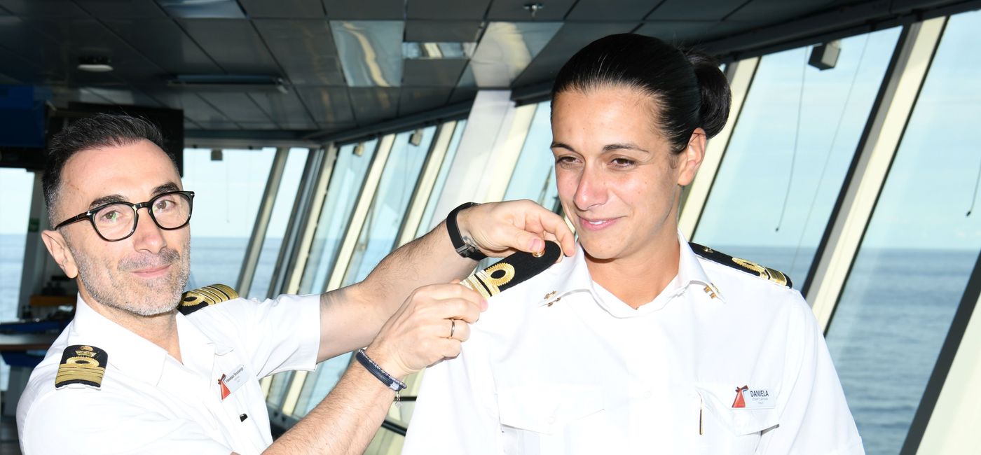 Image: Captain Francesco Bencivenga places the epaulettes on Daniela Gargiulo (Photo Credit: Carnival Cruise Line)