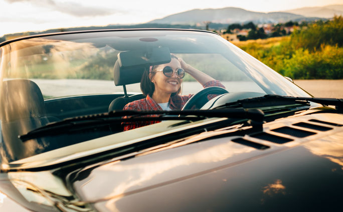 Woman road tripping solo in a stylish convertible