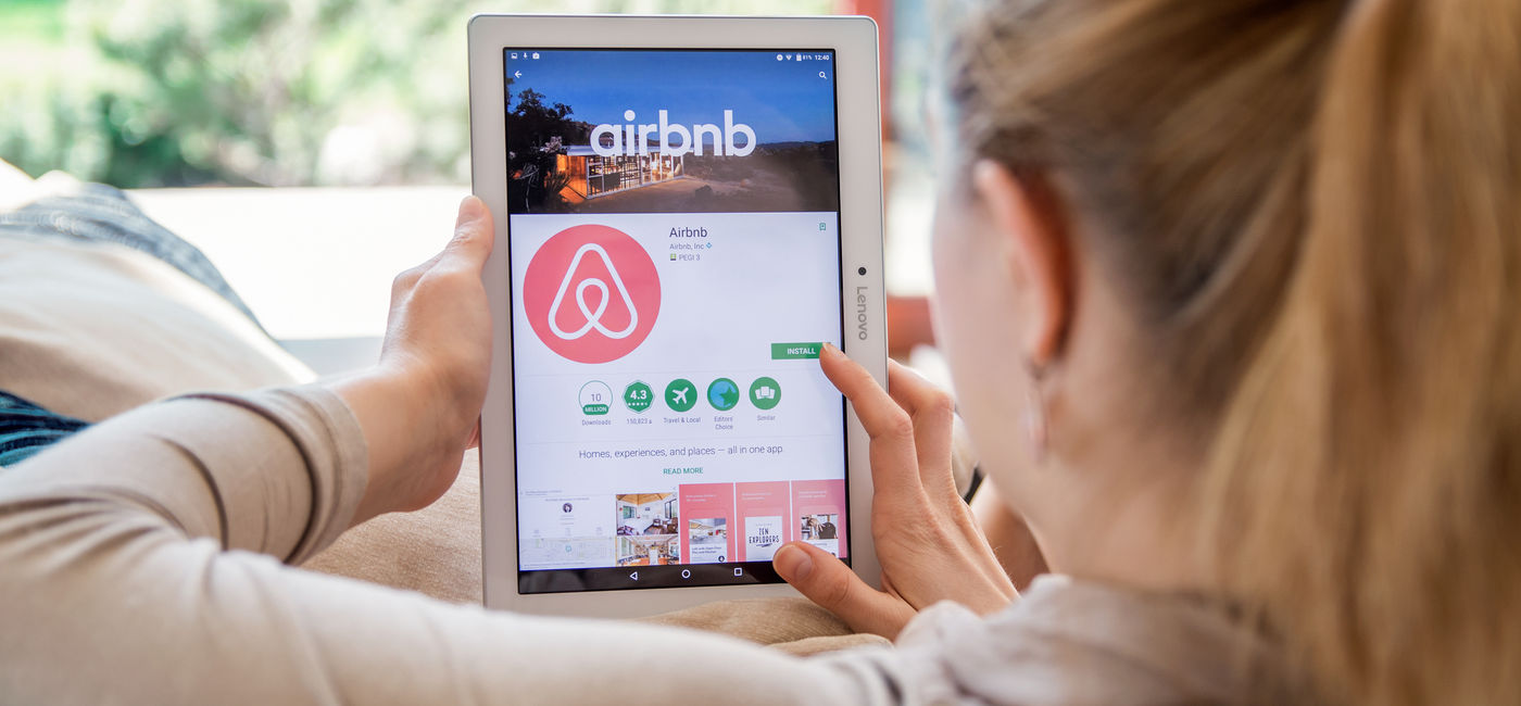 Image: Woman browsing Airbnb listings. (Photo Credit: Daniel Krason/Adobe)