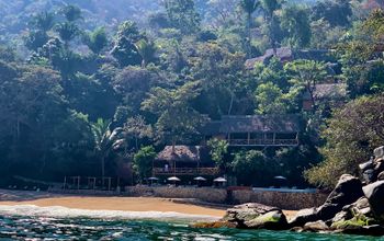 Eco resort on hillside with beach and ocean in foreground