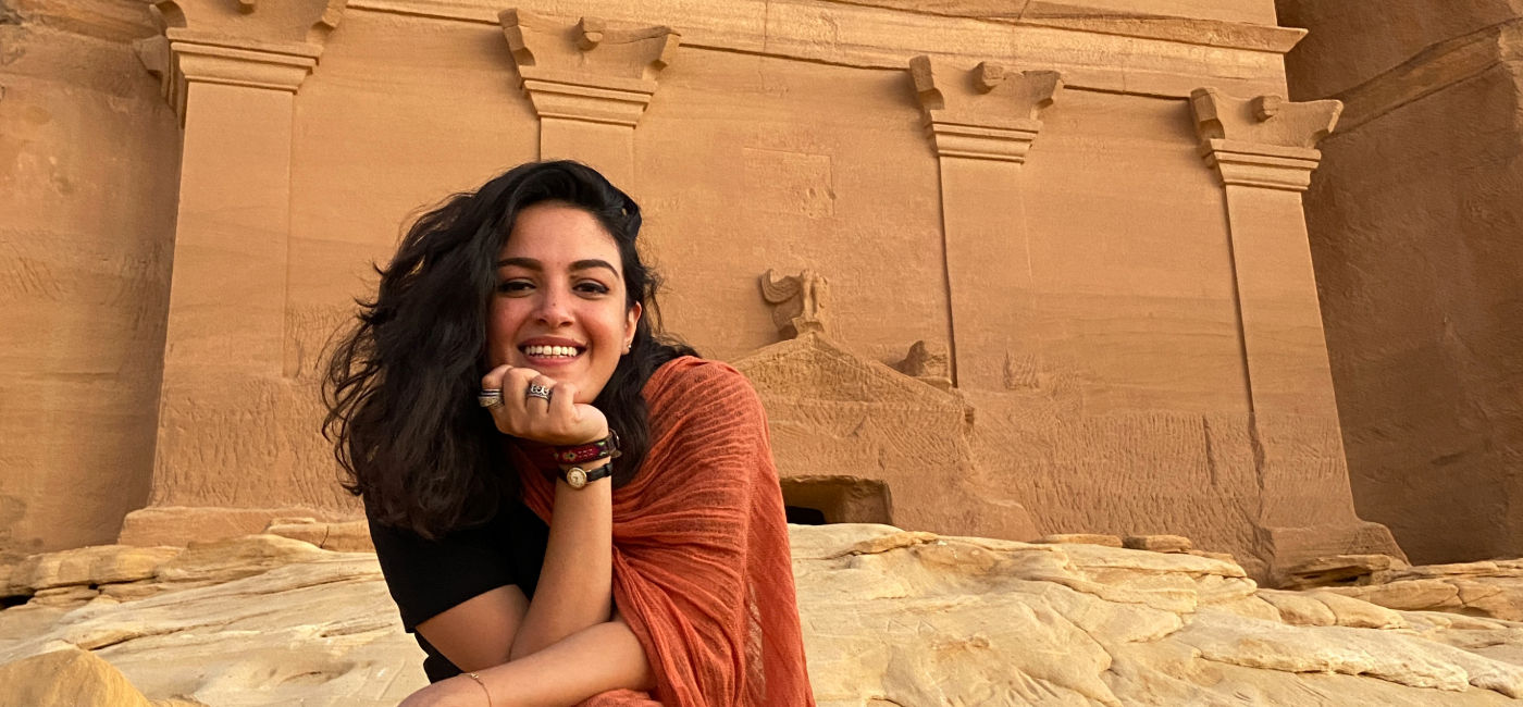 Image: A woman poses in front of Hegra in AlUla, Saudi Arabia.  (Photo Credit: Intrepid Travel)