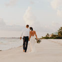 Newlywed couple walking down the beach