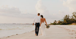 Newlywed couple walking down the beach