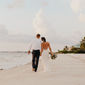 Newlywed couple walking down the beach