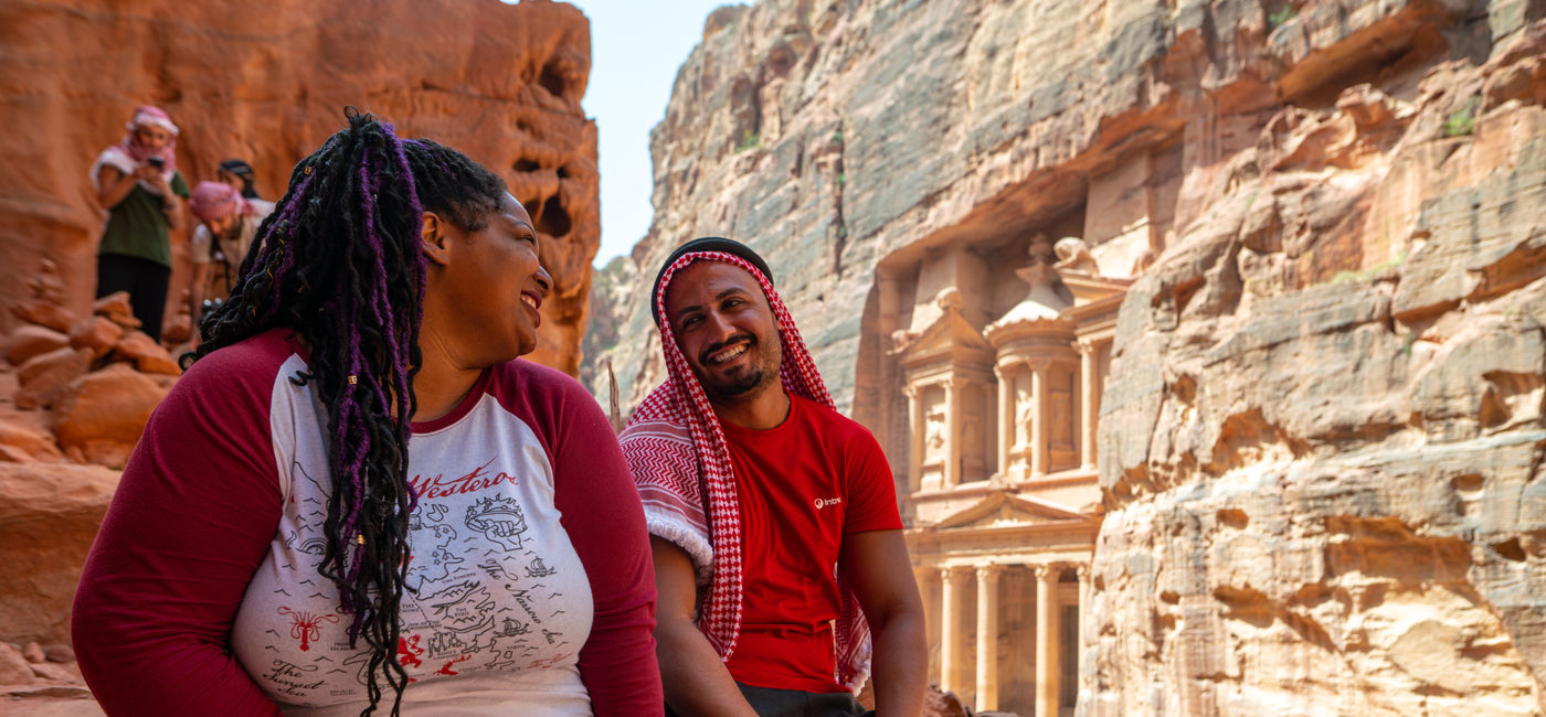 Image: A traveler and an Intrepid tour guide sit together at Petra in Jordan. (Photo Credit: Intrepid Travel)