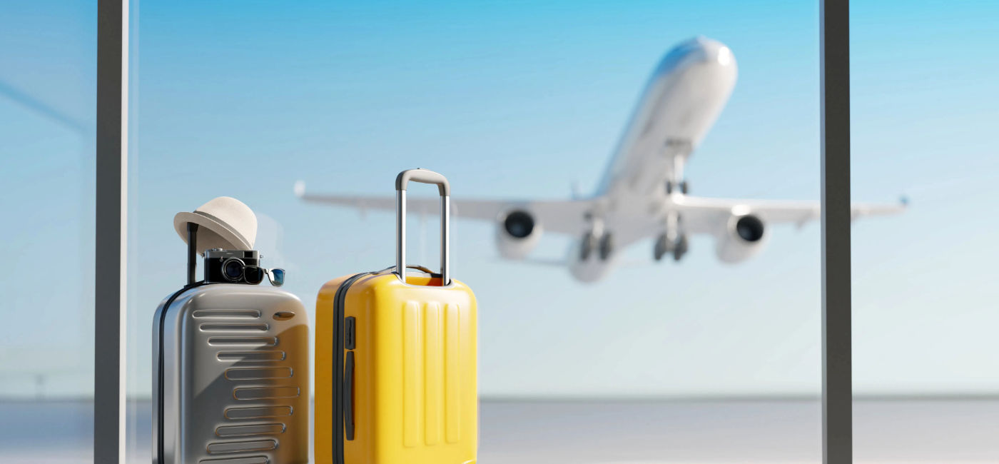 Image: Luggage sitting at the airport with a plane taking off in the background. (Photo Credit: aanbetta / Adobe Stock)