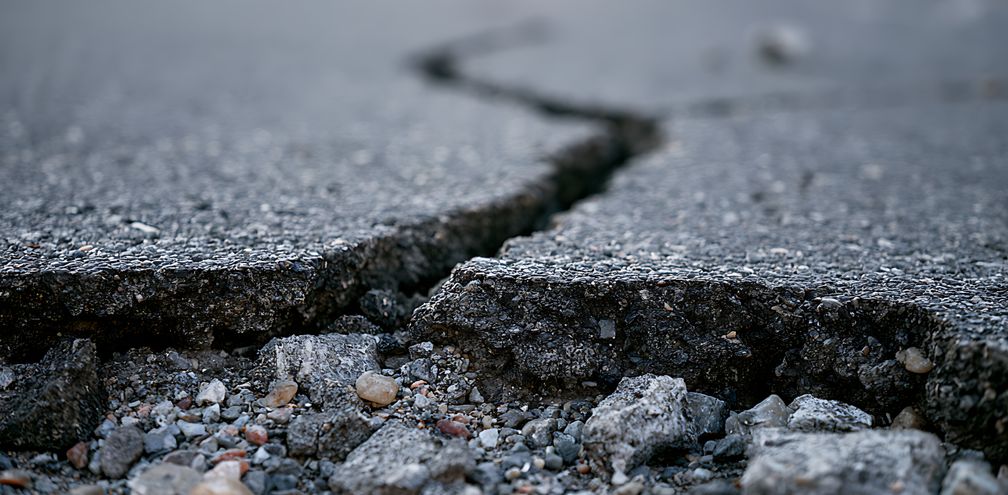 Deep crack in asphalt road surface caused by earthquake damage.
