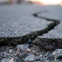 Deep crack in asphalt road surface caused by earthquake damage.