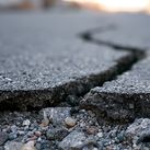 Deep crack in asphalt road surface caused by earthquake damage.