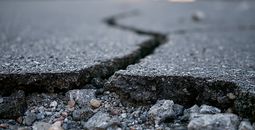 Deep crack in asphalt road surface caused by earthquake damage.
