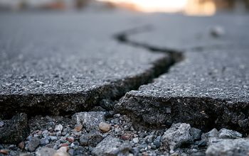 Deep crack in asphalt road surface caused by earthquake damage.