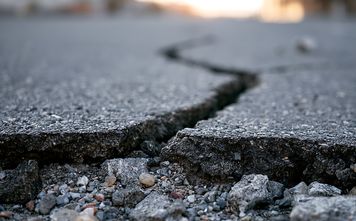 Deep crack in asphalt road surface caused by earthquake damage.