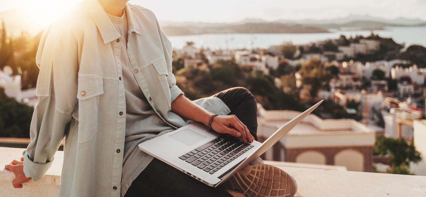 Image: Working on a laptop while traveling. (Photo Credit: olezzo/Adobe Stock)