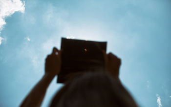 Person watching the solar eclipse through an eclipse viewer. 
