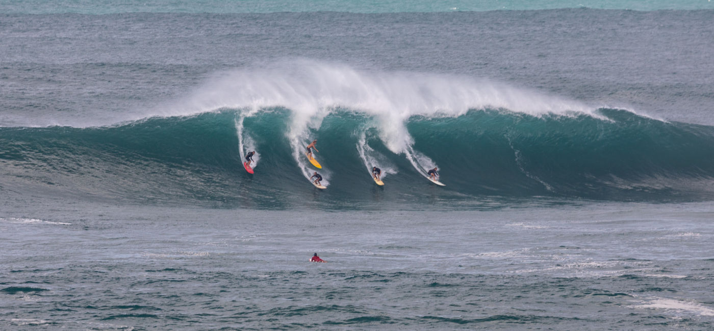 Image: Surfers catching a wave in Waimea Bay on the North Shore of Oahu, Hawaii. (Photo Credit: Adobe/J Westermann-Blawert)