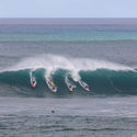 Surfers catching a wave in Waimea Bay on the North Shore of Oahu, Hawaii