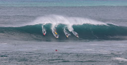 Surfers catching a wave in Waimea Bay on the North Shore of Oahu, Hawaii