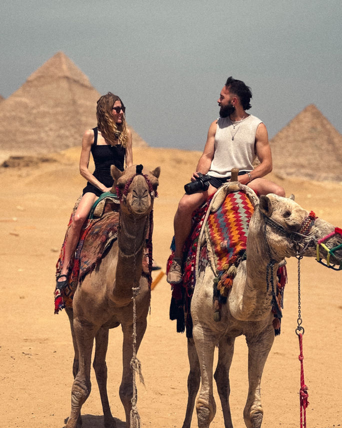Guests riding camels in front of the Great Pyramids at Giza, Egypt.